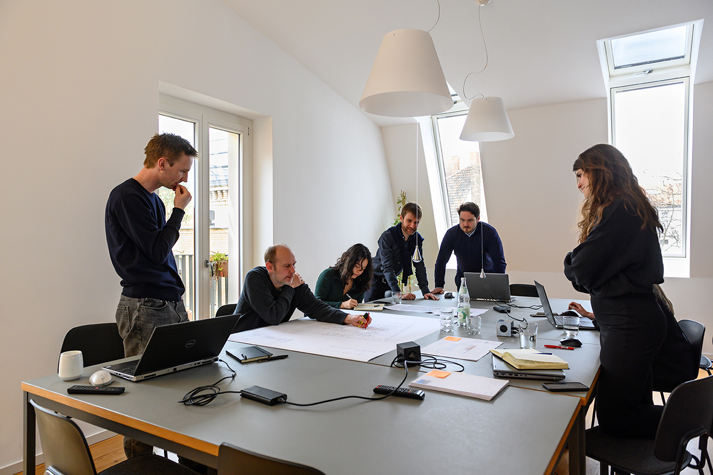 Team von C.F. Møller Architects bei der Besprechung von Plänen an einem großen Tisch