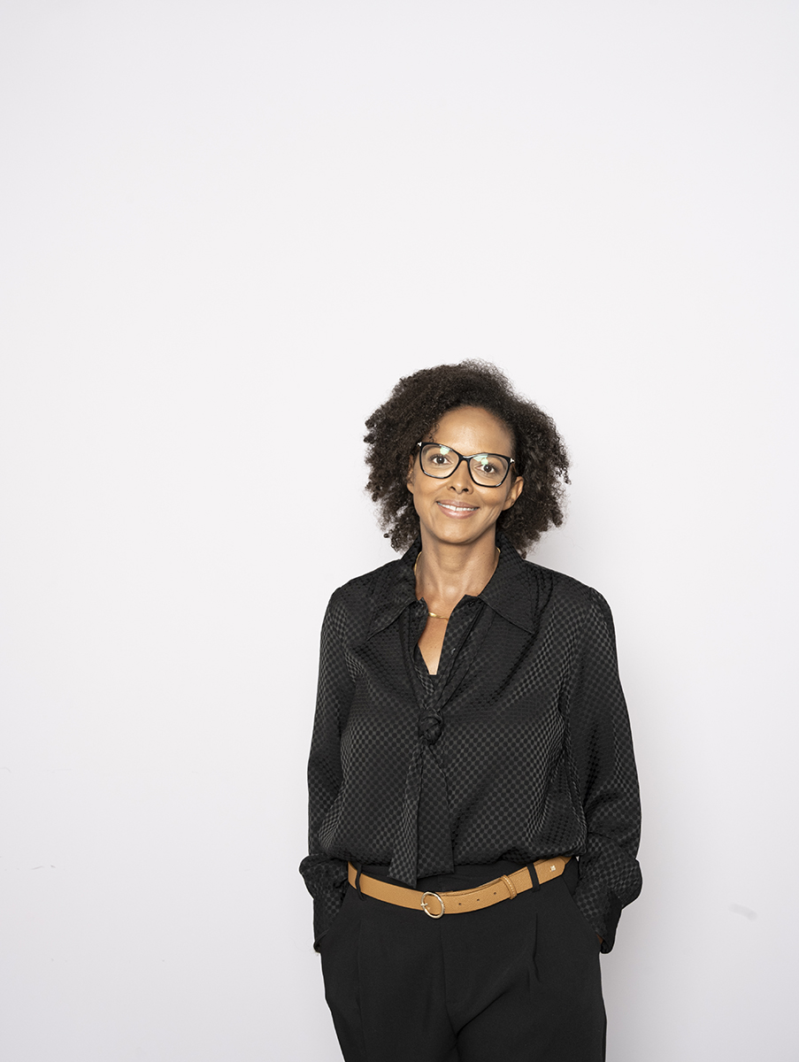 Natascha Thomas in schwarzer Bluse mit Brille, stehend vor hellem Hintergrund