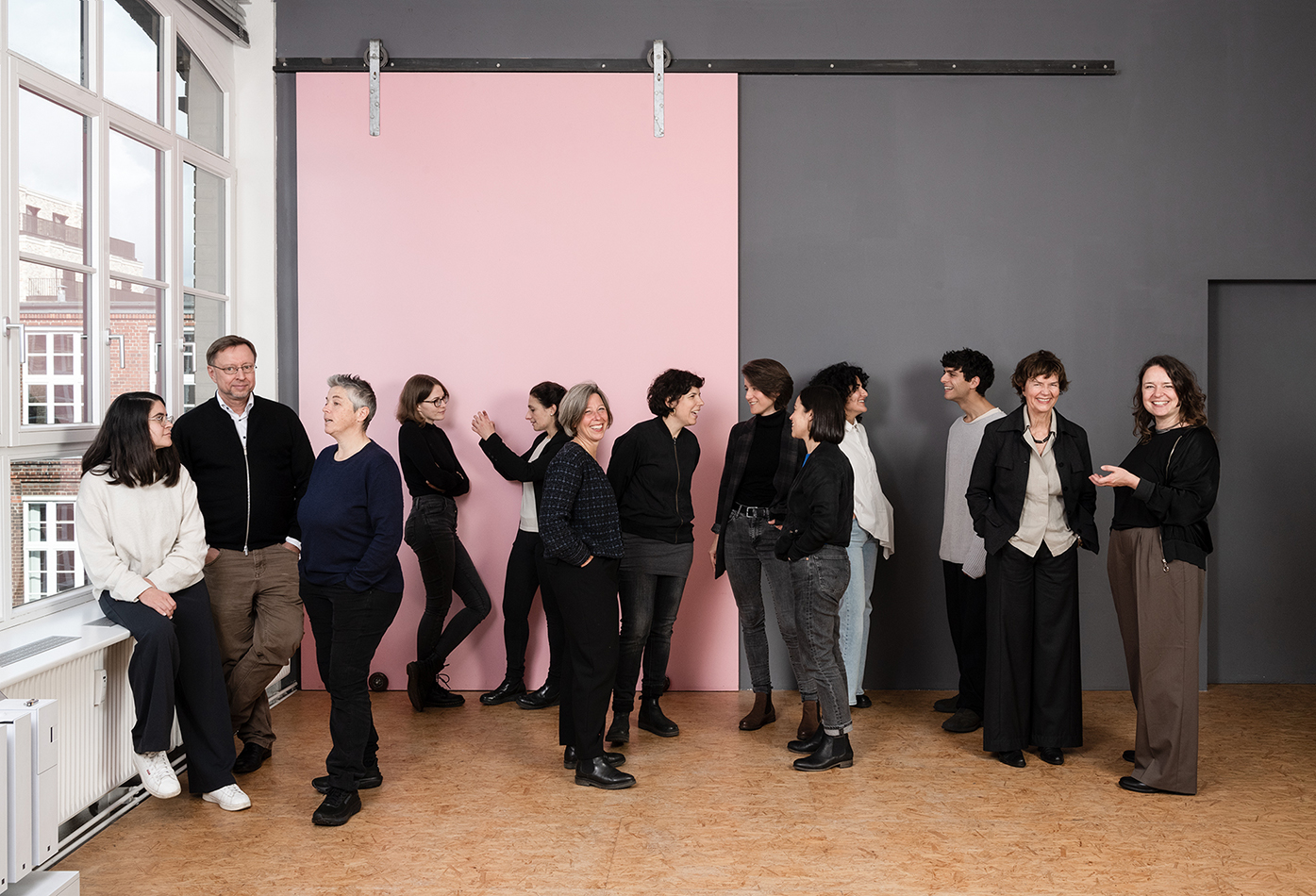 Teamfoto des Büros AL Architekten vor einer rosa Schiebewand