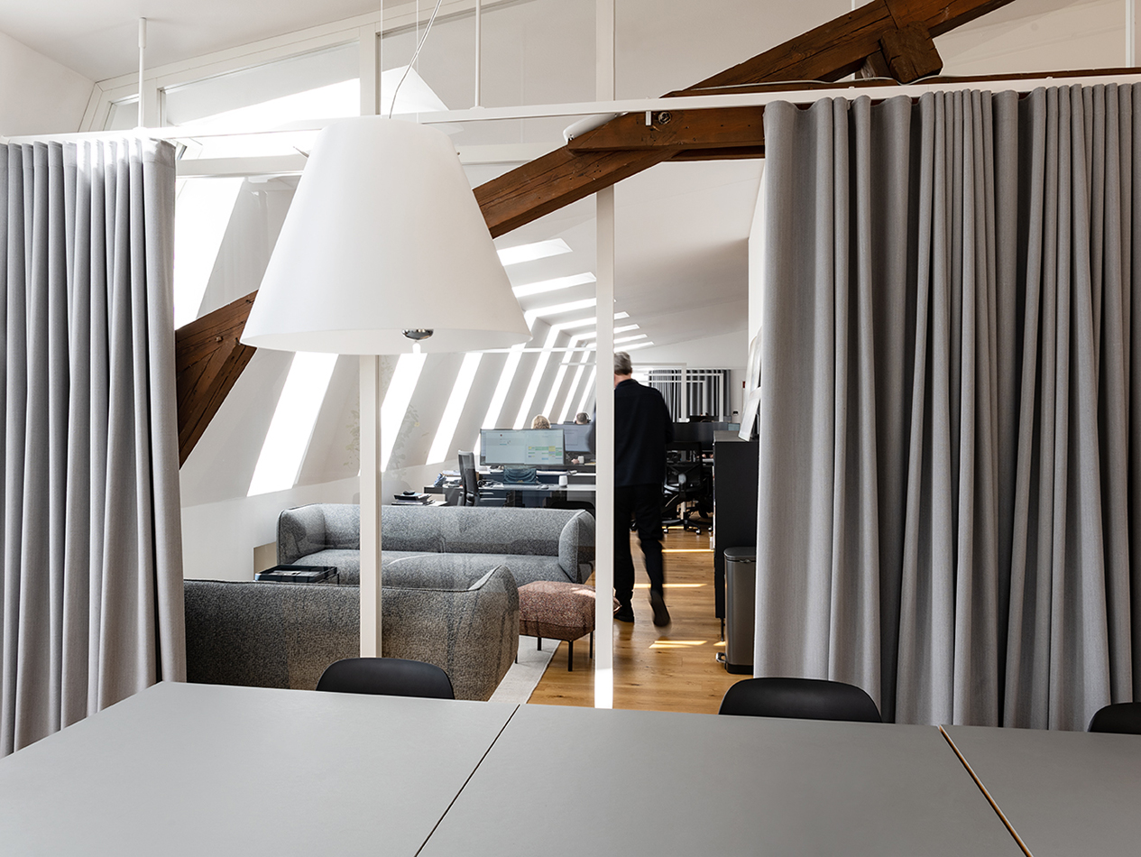 Büroräume von C.F. Møller Architekten mit Holzbalken und grauen Vorhängen