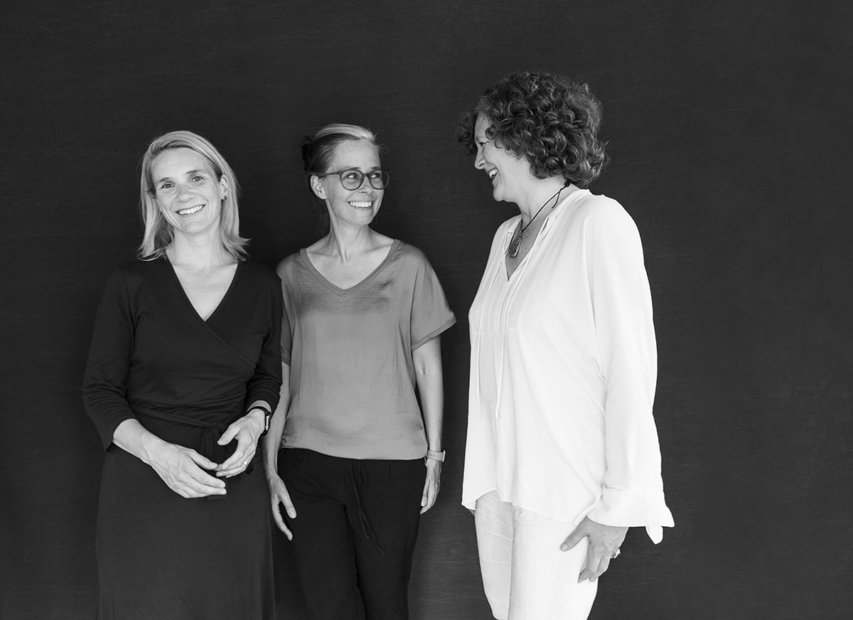 Schwarz-Weiß-Porträt von Julia Erdmann, Nicole Srock.Stanley und Francesca Ferguson, stehend vor dunklem Hintergrund