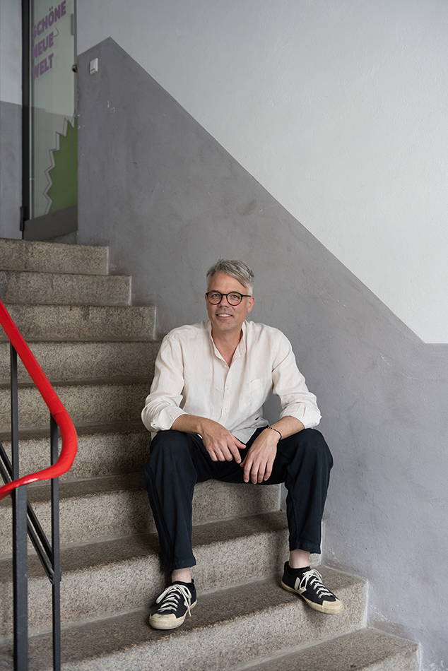 Porträt eines Mannes mit Brille im hellen Hemd, der auf einer Treppe sitzt